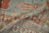 A gentle fold on a distressed Oushak rug highlighting its faded geometric pattern and low pile texture.