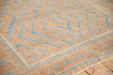 Close-up of distressed Belouch rug: pale blue geometric hook and latch motifs on terracotta.