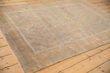Faded terracotta and sapphire blue geometric patterns on a distressed Belouch rug corner.