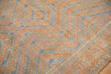 Detail of distressed vintage Belouch rug showing faded pale blue and terracotta hook motifs.