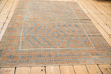 Distressed Belouch rug showing even wear and faded terracotta, pale blue geometric patterns.