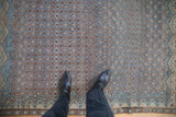 Looking down at the low pile and terracotta Boteh lattice of a distressed antique Malayer rug.
