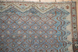 Detailed weave of a distressed Malayer rug corner, showing the Boteh lattice and geometric border.