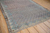 Worn texture of an antique Malayer rug's boteh lattice pattern in soft sapphire and terracotta tones.