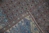 Folded corner of an antique Malayer rug revealing its hand-knotted foundation and pile.