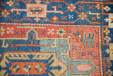 Antique Heriz rug detail: sapphire blue, ruby red, pale gold geometric patterns, with storied texture.