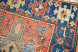 Antique Heriz rug corner shows geometric samovar border, sapphire blue, brick red, and even pile.