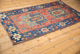 Antique Persian Heriz rug showing sapphire blue border, meandering vine motif, and ivory accents.