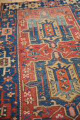 Antique Heriz rug: sapphire blue and ruby red medallion, starburst florals, nuanced abrash, worn pile.