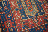 Antique Heriz rug: sapphire blue field with ruby red starburst floral motifs and aged patina.
