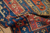 Nuanced sapphire blue and ruby red geometric motifs on an antique Heriz rug's hand-knotted pile with even wear.