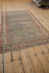 Angled view of a vintage distressed Malayer rug, showcasing the allover fish motif.