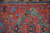 Hand-knotted Heriz rug pile showcasing gem-tone floral and geometric motifs in brick red, teal, and indigo.