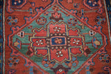 Hand-knotted Heriz rug section: brick red, teal, and sapphire blue geometric floral motifs.