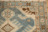 A corner detail of the starburst main border and hand-knotted pile in slate blue, ivory, and coffee brown.