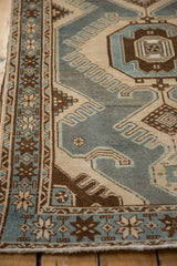 A vintage Malayer rug's starburst border and finned details in dusty blue and coffee brown.