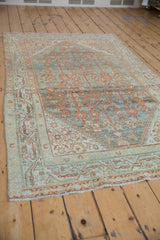 Distressed Serbend rug, terracotta floral patterns on dusty teal with subtle foundation visibility.
