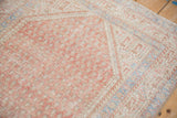 Distressed corner of a vintage Persian rug showing boteh motifs and a pale sapphire blue border.
