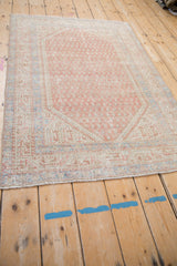Full angled view of a vintage Serbend rug with a distressed, allover boteh pattern.