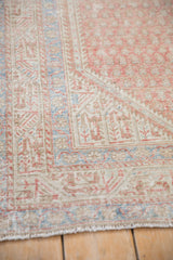 Pale sapphire blue and blush boteh designs on the worn, textured corner of a vintage Persian rug.