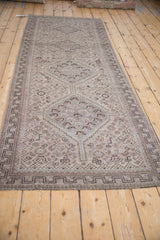 Faded geometric diamond medallions and subtle key-pattern border on distressed Qashqai runner.