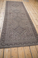 Distressed Qashqai runner close-up: faded gray, brown, ivory diamond motifs and geometric key border.