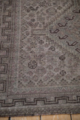 Faded geometric patterns and border of a distressed vintage Qashqai rug runner.