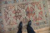 Vintage distressed Caucasian rug showing its geometric medallions and even, decorative wear from above.
