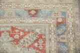 Corner of a vintage Caucasian rug with a geometric dragon-style border and distressed low pile.