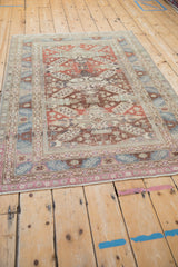Angled view showcasing the worn texture and geometric patterns of a vintage Caucasian rug.