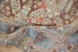 A soft fold in a vintage Caucasian rug reveals its low-pile texture and denim blue geometric border.