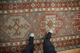 Overhead view of a distressed Karaja runner's repeating hexagonal medallions in brick red and sky blue.