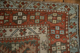 Worn, hand-knotted texture of a Karaja rug corner with red and sky blue geometric borders.