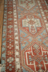 Angled view of the distressed Karaja runner's geometric patterns in sky blue and brick red.