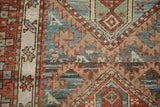 Close-up of the worn, hand-knotted pile showing serrated geometric motifs in red, blue, and beige.