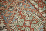 Visible knot heads and a hexagonal shield motif in jade green and red on a vintage Karaja rug.