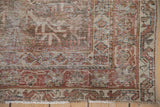 Distressed Mahal rug corner showing faded tree of life field, palmette-vinery border, and fringe.
