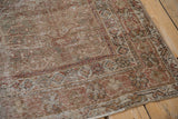 Distressed Mahal rug corner: dusty terracotta, beige floral border, worn pile, bound side.