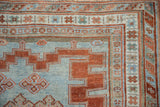 Distressed antique Caucasian rug showcasing geometric stepped border in powder blue and brick red.