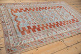 Corner detail of distressed antique Caucasian rug, featuring stepped red border and pale blue field.