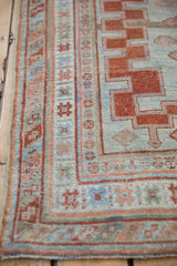 Close-up of distressed antique Caucasian rug's stepped border, powder blue and brick red tones.
