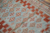 Abrashed powder blue field with distressed red quatrefoil guls on antique Caucasian rug.