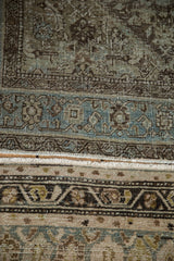 Distressed vintage Persian rug's pile texture, pale blue, charcoal, showing fringe and faint foundation.