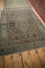 Distressed vintage Persian rug corner with dusty blue border, faint foundation visible.