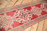 Vintage Oushak runner's cherry red field, ivory medallion, blue quatrefoil motif, and ribboned vine border.