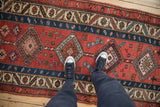 Geometric diamond medallions and stylized animal figures on a madder red antique Persian runner.