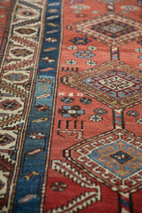 Detail of an antique Persian runner's geometric medallions and stylized figures on a madder red field.