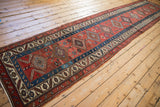 Antique Persian runner laid out full length, showing the red and blue geometric medallion column.