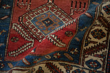 Folded antique Persian rug showing textured pile and geometric hook-and-latch medallions.