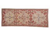 Antique distressed Kazak rug runner with large-scale starburst eagle motifs in terracotta, sand, and yellow.